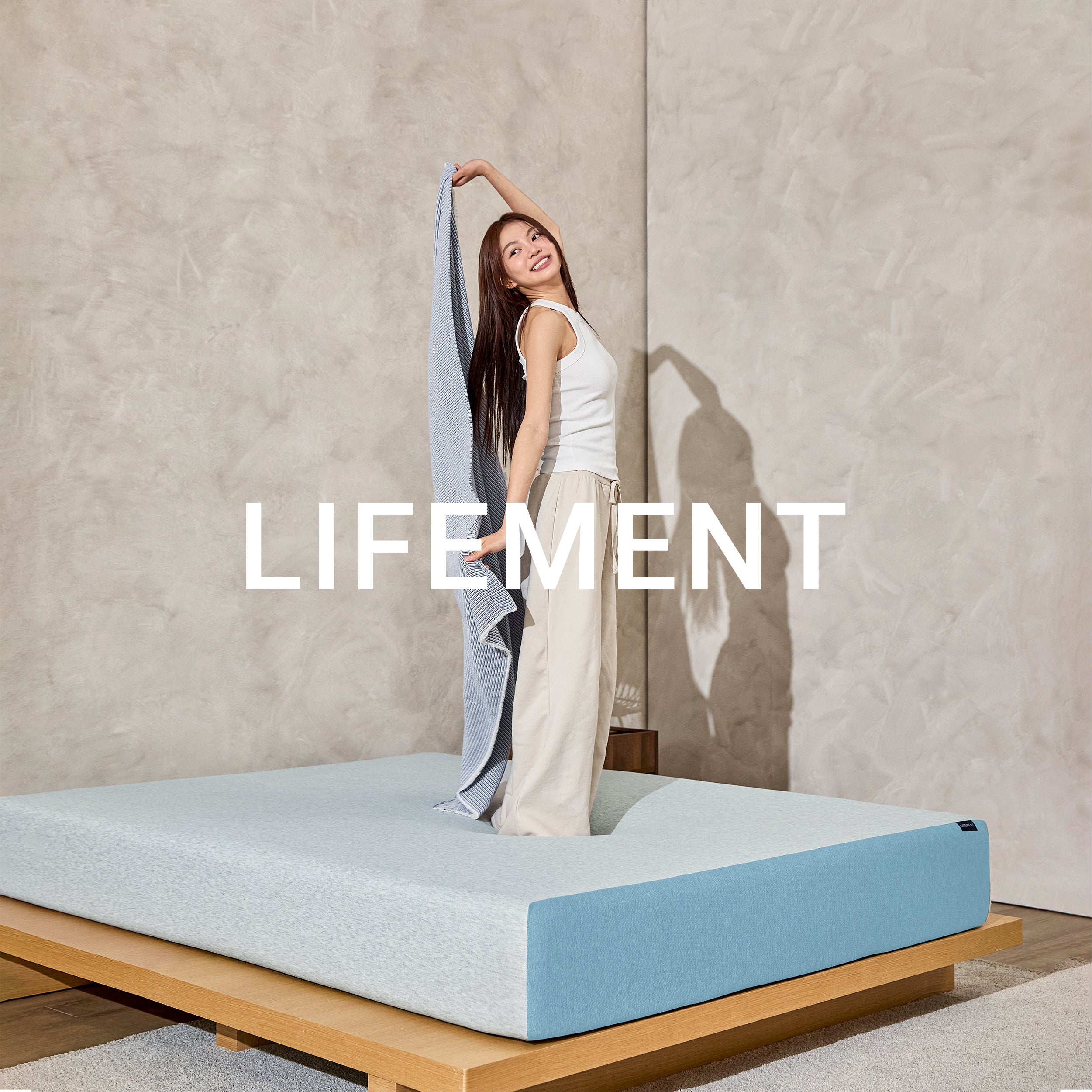 Woman standing on a Lifement Basic Cooling Gel Memory Foam Mattress in a bright room with Lifement branding