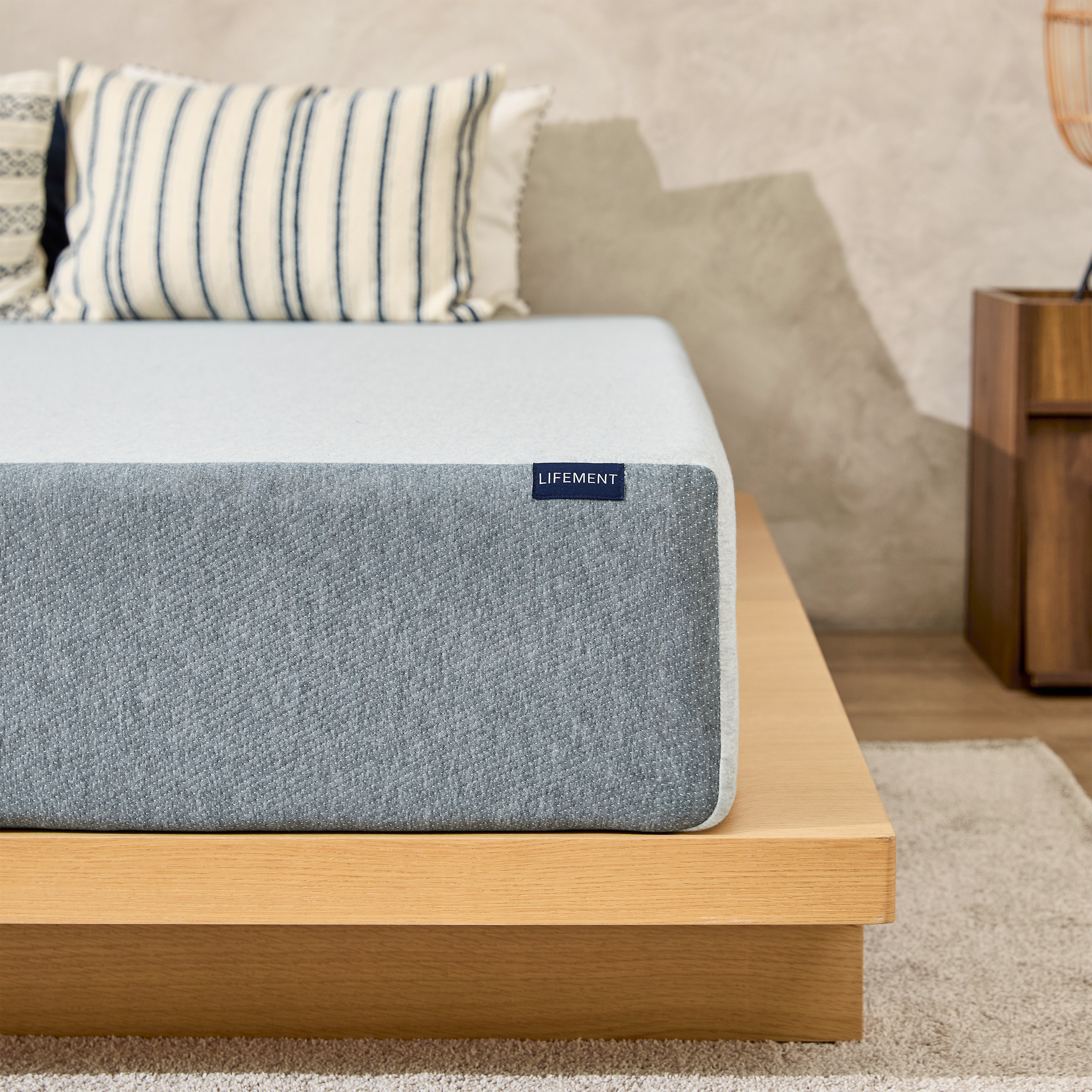 Lifement Basic Graphite Memory Foam Mattress with gray breathable cover on a natural wood bed frame in a bedroom with striped accent pillows