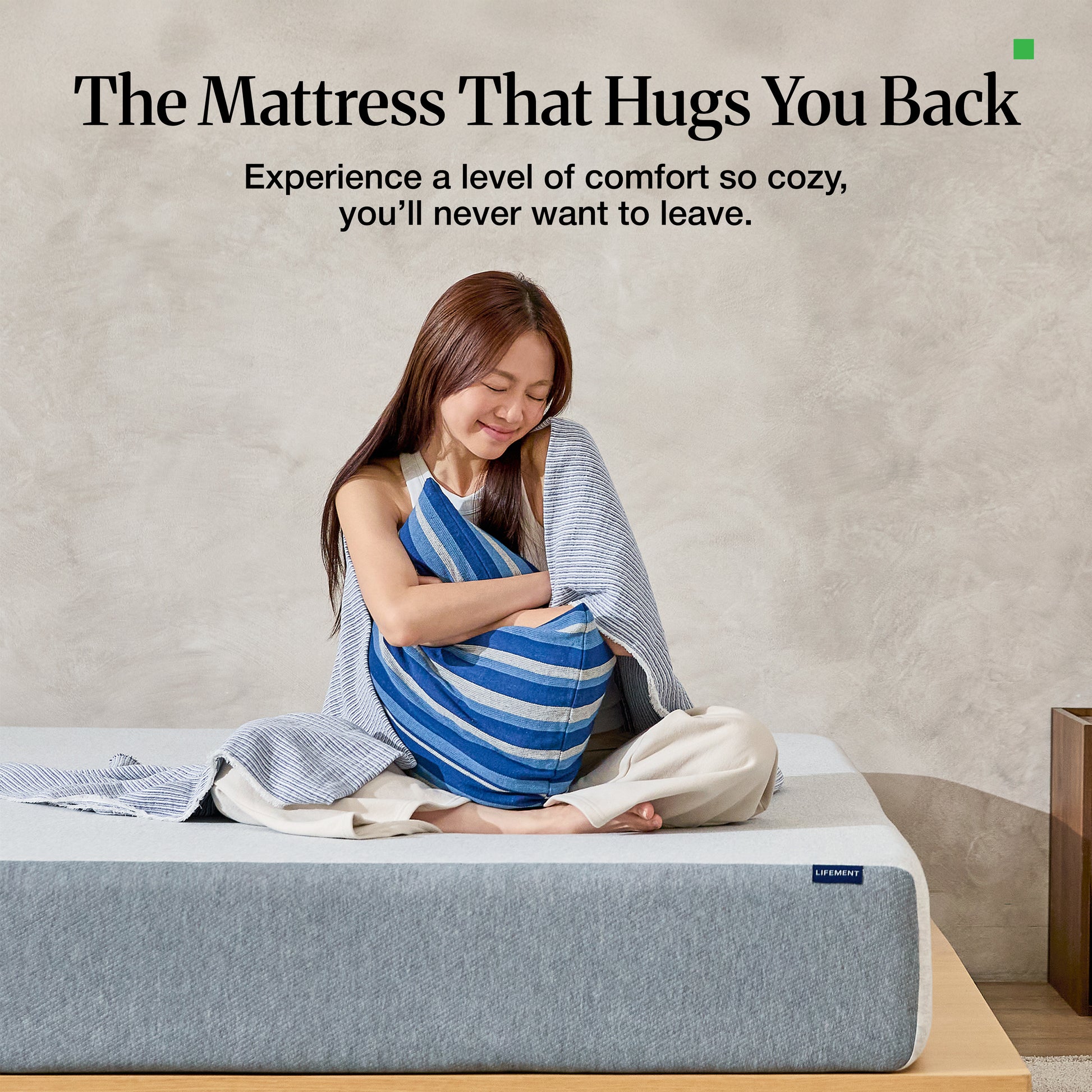 Woman relaxing and hugging pillow on a Lifement Basic Graphite Mattress showcasing plush comfort and support